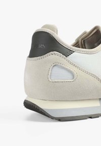 Baskets en suede gris clair avec un panneau en tissu texturé, des accents en cuir gris foncé et une semelle en caoutchouc dotée d'un motif de grip texturé.