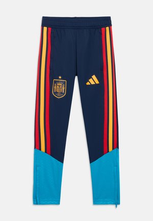 Blaue Sporthose mit roten und gelben Seitenstreifen, versehen mit einem spanischen Wappen und dem Adidas-Logo. Knöchelreißverschlüsse und weiche Stoffstruktur.