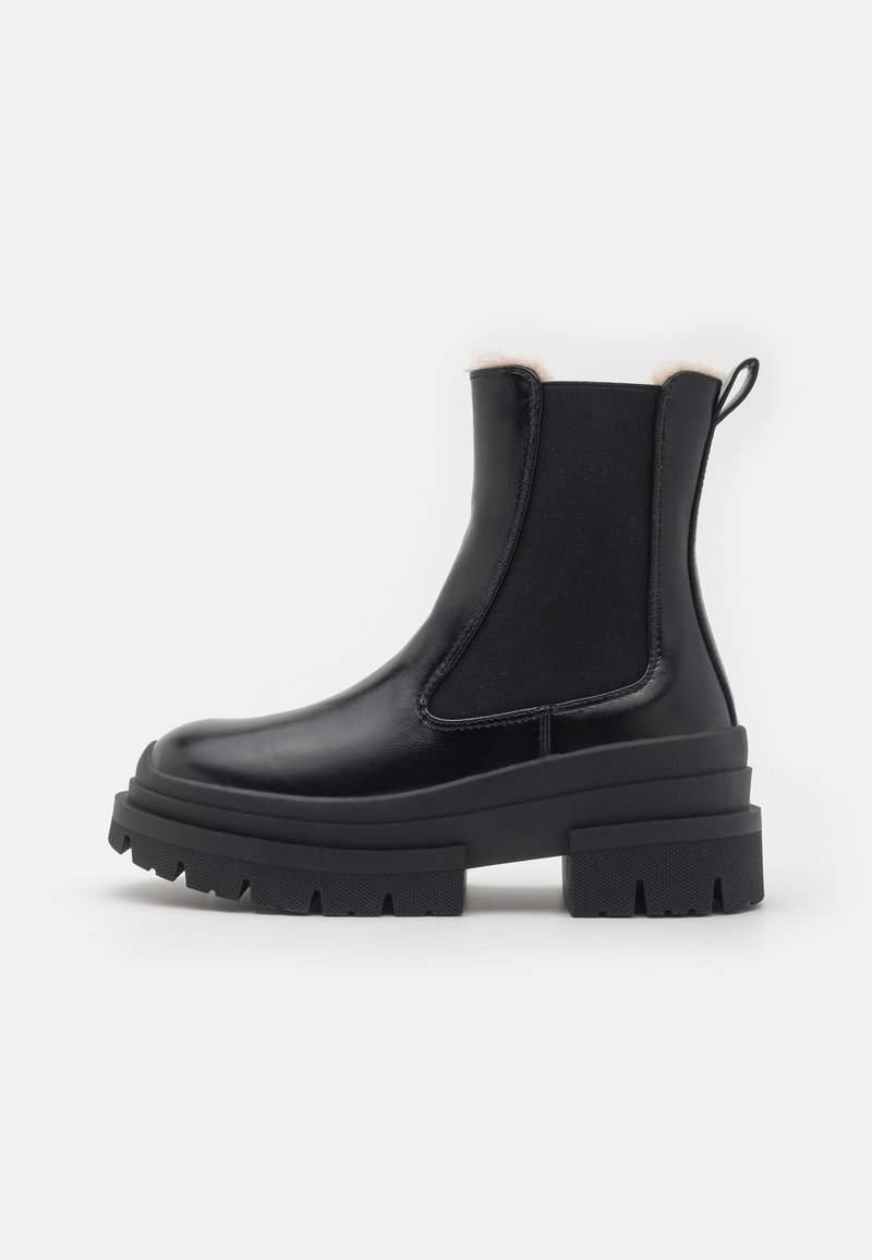 Μαύρες ankle μπότες με λείο δερμάτινο φινίρισμα, χοντρή καουτσούκ σόλα και ελαστικές πλάγιες πάντες; η μαλακή επένδυση φαίνεται πάνω από τον γιακά.