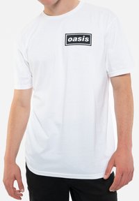 White cotton t-shirt with short sleeves, featuring a black rectangular logo that reads "oasis" on the upper left side.