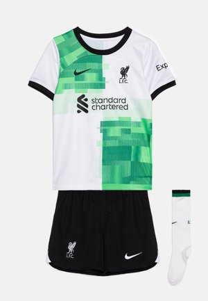 Conjunto de camiseta juvenil del Liverpool FC que presenta un diseño pixelado en blanco y verde, pantalones cortos negros y un par de calcetines blancos con detalles verdes.