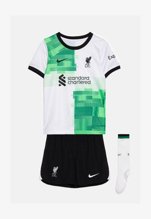 Conjunto de camiseta juvenil del Liverpool FC que presenta un diseño pixelado en blanco y verde, pantalones cortos negros y un par de calcetines blancos con detalles verdes.