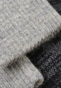 Stofa din lână texturată gri și neagră; prezintă un model de tricot cu nervuri, cu o suprafață moale și pufoasă și o țesătură mai groasă.