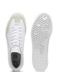White sneakers with a suede toe cap, textured white sole, and flat laces; PUMA branding on the tongue and sole.