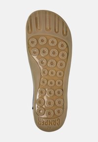 Sole di una scarpa con una base in gomma color beige, dotata di grip circolari e scanalature per la trazione, con l'etichetta "Campers 42" di lato.