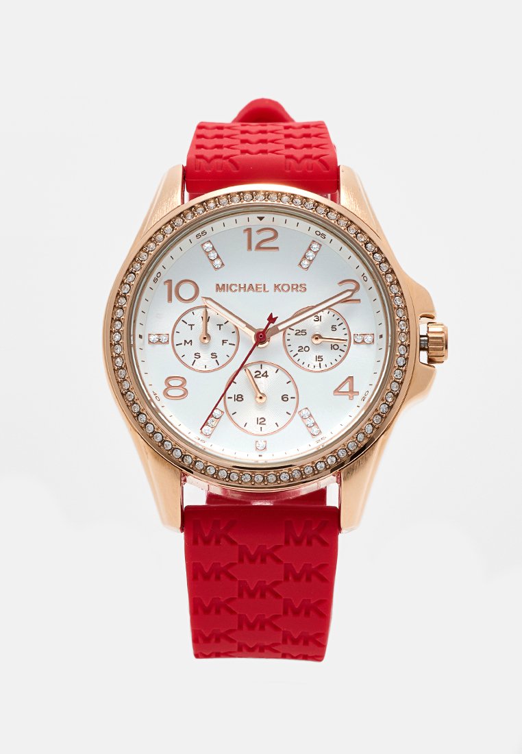 Montre en or rose avec bracelet en caoutchouc rouge. Cadran blanc affichant trois sous-cadrans et des accents en cristal. Chiffres marqués aux 2, 4, 8, 10 et 12.
