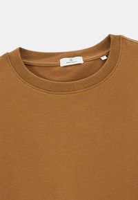 Sweatshirt en coton marron avec un col rond côtelé et une étiquette à l'intérieur du col. Texture douce avec un design uni.