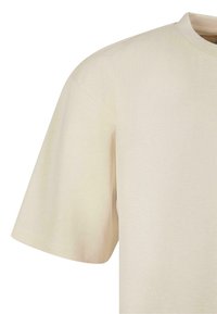 Beige bomulds t-shirt med loose fit, rund hals og korte ærmer. Glat tekstur med minimal syning.