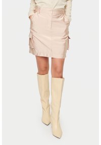 Ljusrosa satäng mini kjol med sidofickor, subtil glans och rak skärning. Matchad med knälånga beige stövlar.