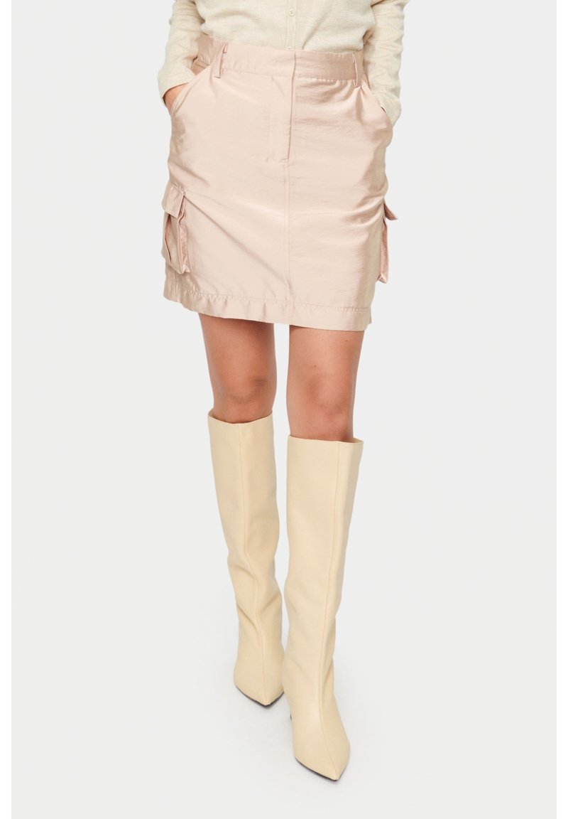 Ljusrosa satäng mini kjol med sidofickor, subtil glans och rak skärning. Matchad med knälånga beige stövlar.