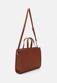Sac fourre-tout en cuir marron avec deux poignées supérieures et une bandoulière ajustable. Présente une forme rectangulaire et des détails de surpiqûre contrastés.