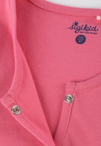 Rosa Baumwollhemd mit rundem Ausschnitt, ausgestattet mit Druckknöpfen, glatter Textur und einem Etikett, das die Größe 104 (4 Jahre) von sigikid angibt.