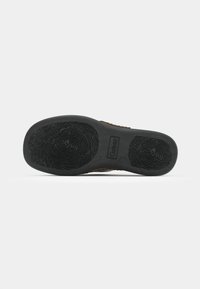 Semelle de chaussure en caoutchouc noir avec un motif texturé et le logo "Gabior", présentant une légère courbure et un design flexible pour une meilleure adhérence.