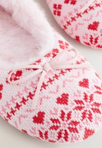 Zacht roze en rode gebreide slippers met hart- en sneeuwvlokpatronen, pluizige binnenvoering en een klein strikje aan de voorkant.