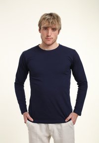 Marinblå långärmad skjorta med rund halsringning, tillverkad av mjukt material, som sitter åtsittande runt bålen och armarna, med minimala sömnadsdetaljer.