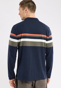 Polo à manches longues de couleur bleu marine avec des rayures horizontales en orange, blanc et vert olive. Il possède un col et une texture de tissu douce.