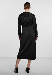 Black satin long dress with long sleeves, a fitted waist, and a straight cut, featuring a round neckline and smooth texture.
