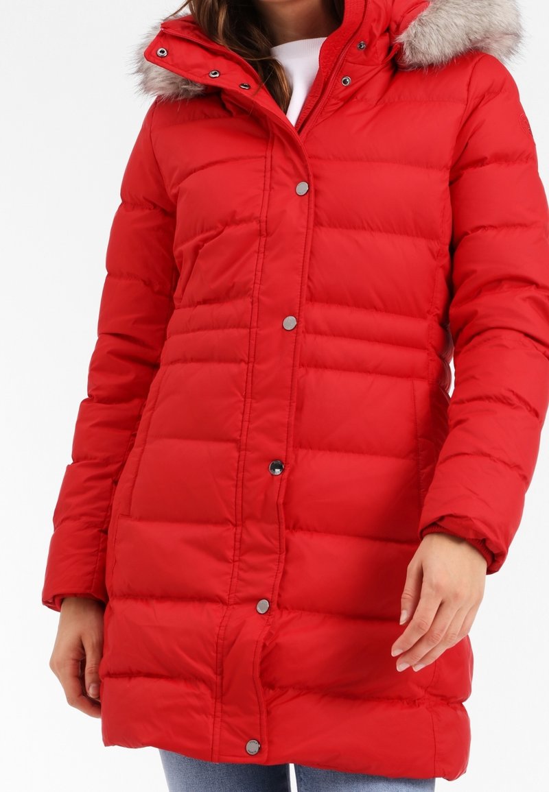 Röd puffig jacka med huva och fuskpäls på kanten. Jackan har ett quiltat mönster, tryckknappar och två sidofickor.