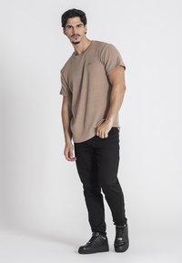 Beige pruhované tričko s krátkým rukávem, kombinované s černými slim-fit džíny a černými botami. Jednoduchý design, měkká textura a volný střih.
