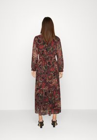 Maxi šaty v mnohobarevném paisley vzoru, s dlouhými rukávy, vypasovaným pasem a splývavým siluetou. Texturovaná látka, průsvitný finiš.