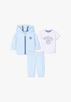 Jasnoniebieski dres składający się z bluzy z kapturem na zamek, białej koszulki z grafiką oraz pasujących niebieskich spodni. Miękka, bawełniana tekstura w całym zestawie.
