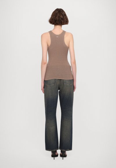 Brun ribbet tank topp med en tettsittende design, parret med vide falmede blå jeans. Svarte hæler fullfører antrekket.