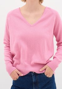 Różowy sweter z dekoltem w serek, z prążkowanymi mankietami i obrębem, wykonany z miękkiego materiału, z długimi rękawami i swobodnym krojem.