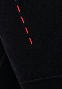 Gros plan d'un tissu noir texturé avec une ligne rouge en pointillé cousue sur la surface.