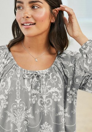 Gray floral-patterned blouse with a round neckline, drawstring detail, and elastic cuffs. Features delicate white botanical designs.
