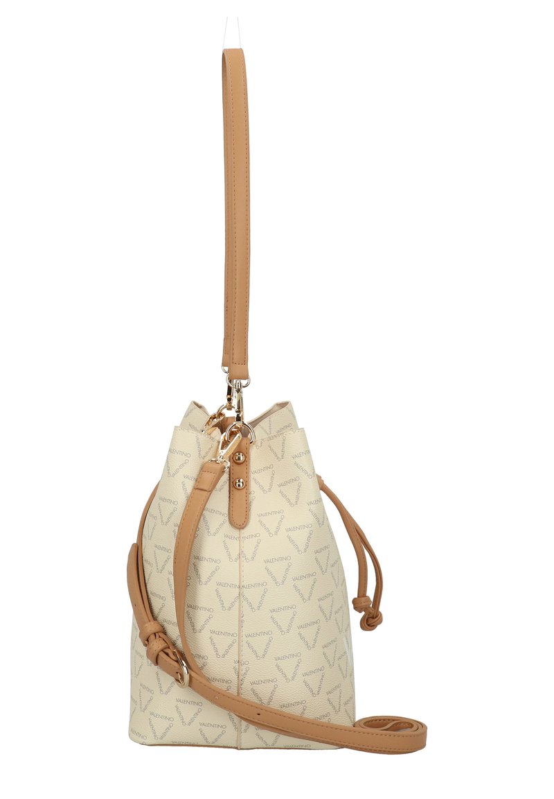 Eimerhandtasche aus strukturiertem cremefarbenem Material mit einem sich wiederholenden Logo-Muster, Akzenten aus braunem Leder und einem verstellbaren Schultergurt. Hardware in goldfarbener Ausführung.
