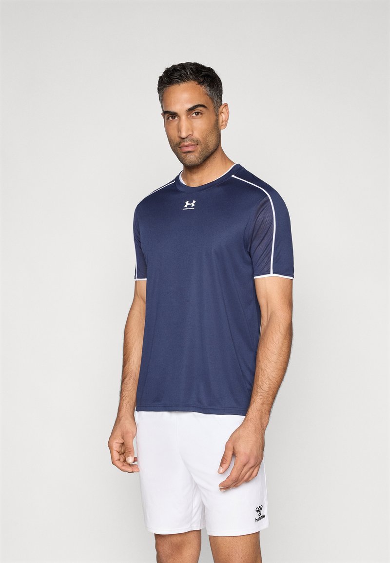 Αθλητική μπλούζα ναυτικού μπλε χρώματος από ελαφρύ, διαπνέον ύφασμα με λευκές διακοσμητικές ραφές. Κοντά μανίκια και λαιμόκοψη τύπου crew neck. Περιλαμβάνονται λευκά σορτς.