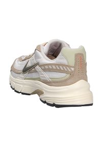 Sneaker Nike con una toma in rete, dettagli beige e verde chiaro, suola intermedia spessa color crema e suola esterna in gomma nera. Presenta dettagli testurizzati.