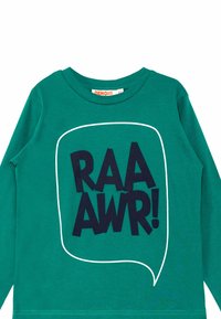 T-shirt verde a maniche lunghe con una grande grafica testuale nera che dice "RAA AWR!" all'interno di un contorno di una nuvoletta bianca. Materiale in cotone morbido.
