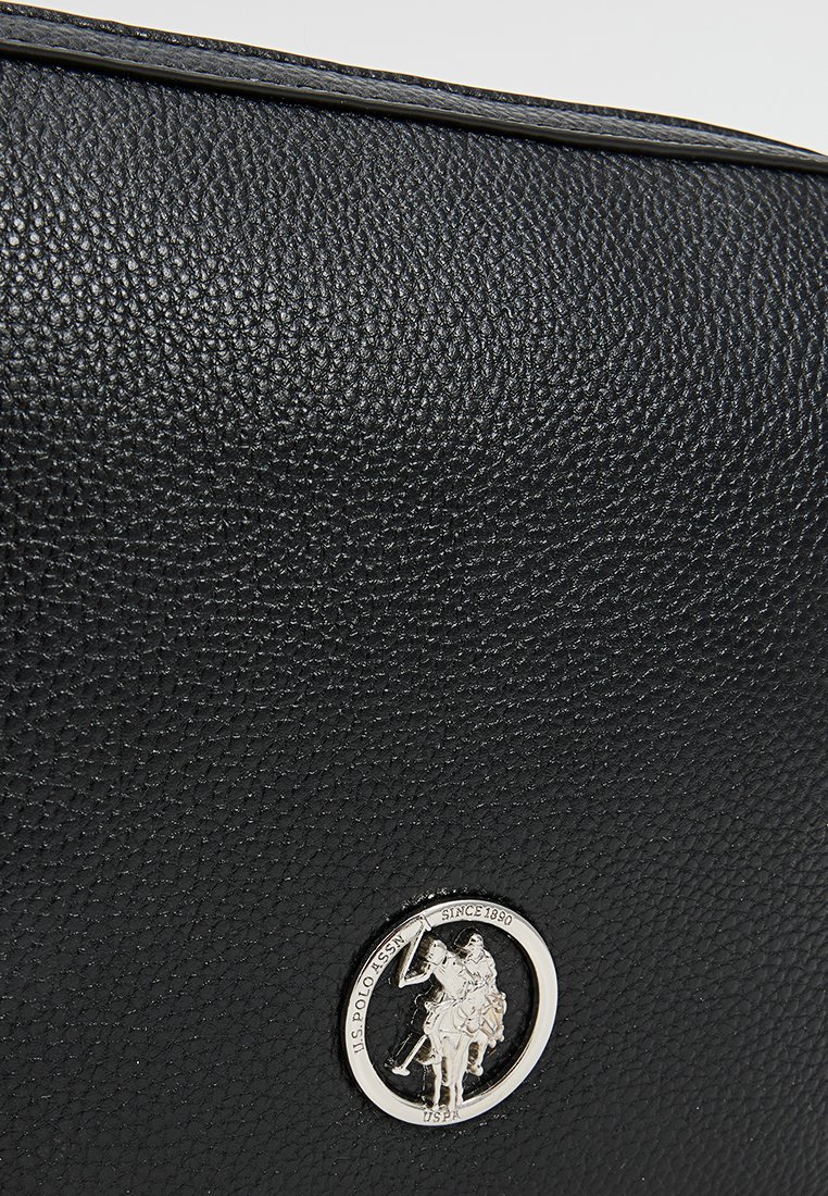 Bolso de cuero negro texturizado con un logo plateado en forma de círculo que presenta un motivo de caballero. Diseño plano y estructurado con un detalle en el borde superior.