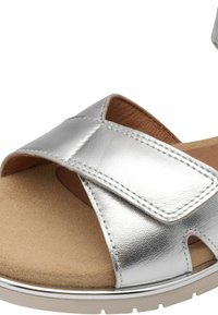 Sandal in metallo argentato con un design a fascia incrociata, soletta in morbido color beige e superficie testurizzata. Presenta una punta tonda e una suola leggera.