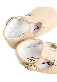 Le scarpe in pelle beige presentano una punta arrotondata, design con ritagli e una fascetta con fibbia. L'interno è rivestito in morbido bianco e sono visibili dettagli di cucitura.
