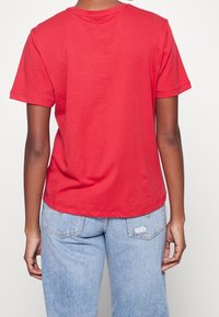 Camiseta de algodón roja con mangas cortas y cuello redondo. Presenta un ajuste relajado y una textura suave. Vista trasera sin logos visibles.