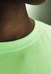 Κοντινό σε λαιμό και κάτω μέρος προσώπου ατόμου με ανοιχτό πράσινο υφασμάτινο πουκάμισο με στρογγυλή λαιμόκοψη.