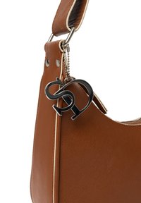 Braune Lederhandtasche mit silbernem Zubehör, strukturierter Oberfläche und einem dekorativen Anhänger mit einem stilisierten Logo an einer Kette.