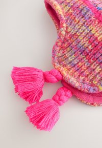 Gestrickte Mütze in lebhaften Pink-, Lila- und Gelbtönen. Verfügt über dickes Garn, abgerundete Form und zwei große, pinke Quasten auf jeder Seite.