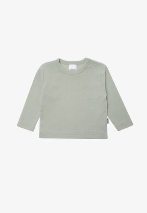 Long-sleeve cotton t-shirt in soft sage green with round neckline and two snap fasteners on one shoulder. Smooth texture, minimal design.