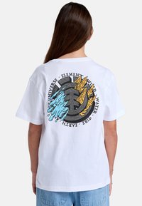 Witte katoenen t-shirt met een cirkelvormige afbeelding op de achterkant, met blauwe water- en oranje vuur-elementen, omringd door tekst en een zwart embleem.