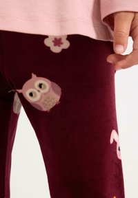 Maronfarvede leggings lavet af blødt stof, med lyserøde og hvide ugle- og blomsterprint. Fremhævet med en glat tekstur og elastisk talje.