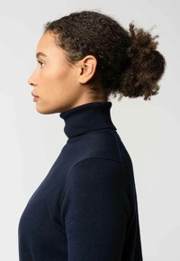 Donkerblauwe coltrui gemaakt van een zachte, gemêleerde brei stof, met een slim fit ontwerp en geribde kraag. Zijaanzicht.