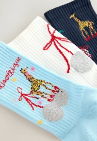 Tre par ribbede sokker: lyseblå med et giraff-design, hvide med en rød sløjfe og marineblå med farverige detaljer.