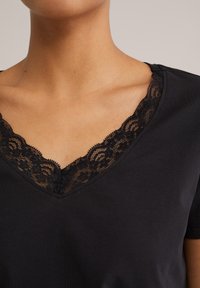 Black short-sleeve top featuring a V-shaped neckline with delicate black lace trim. Smooth fabric with a soft texture.