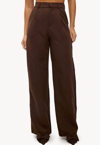 Un pantalon large marron avec une taille haute, un devant plissé et des accents en forme de nœud à l'ourlet. Confectionné dans un tissu lisse pour un look ajusté.