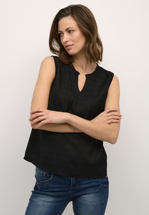 Haut sans manches noir avec un motif texturé, encolure ronde et une petite ouverture en forme de clef à l'avant. Associé à un jeans en denim.