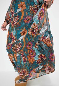 Maxi-Kleid mit einem blauen, orangefarbenen und lila Blumenmuster. Hergestellt aus leichtem, plissiertem Stoff mit gerafften Details am Saum.