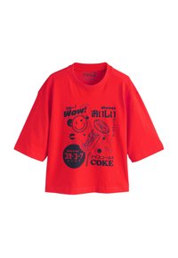 Crvena pamučna majica s kratkim rukavima i okruglim izrezom. Na prednjoj strani ima crni grafički otisak s logotipima Coca-Cole i japanskim tekstom.